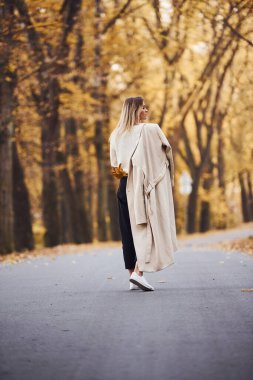 Gündüz vakti güz ormanlarında yolda yürüyen esmer bir kızın portresi..