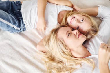 Anne kızıyla birlikte beyaz yatağa uzandı..