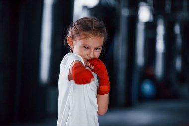 Spor giyinmiş küçük bir kızın portresi spor salonundaki spor gününde. Boks kavramı.