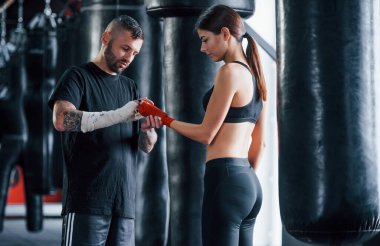 Sargı bezi takıyordu. Genç dövmeli boks koçu spor salonunda genç bir bayana ders veriyor..