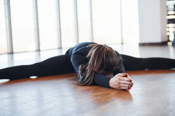 身穿黑色运动服的胖女人伸懒腰躺在地板上 — 图库照片