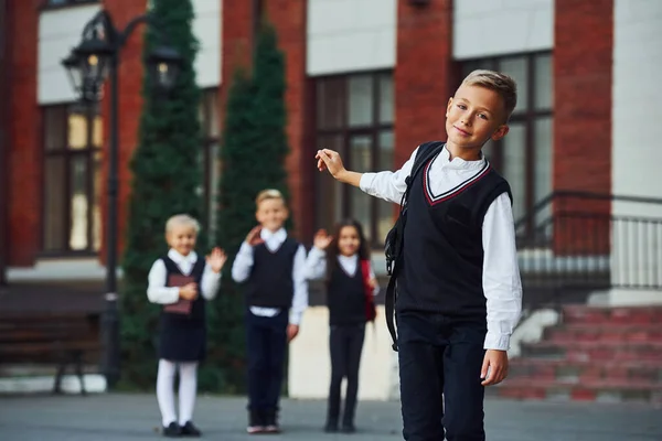 学校の制服を着た子供たちのグループが教育棟の近くで屋外で一緒にカメラをポーズ — ストック写真