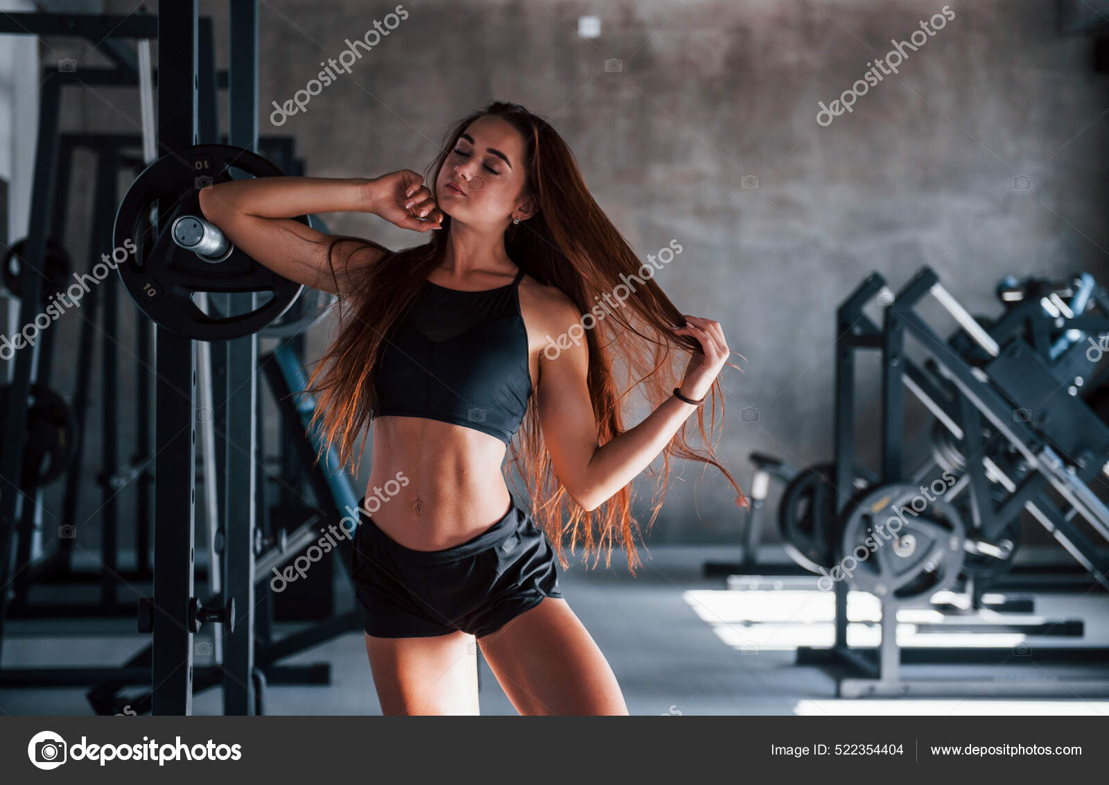 Mujer joven fitness con cuerpo delgado y ropa deportiva negra está en el  gimnasio.