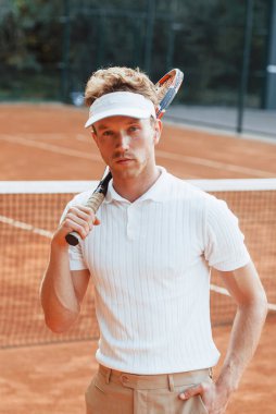 Kamera için poz vermek. Spor elbiseli genç tenisçi dışarıda..