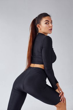 Twerk dansı. Stüdyoda beyaz arka planda siyah elbiseli bir kadın var..