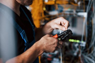 Üniformalı genç adam sunucu odasında internet teçhizatı ve kablolarla çalışıyor..