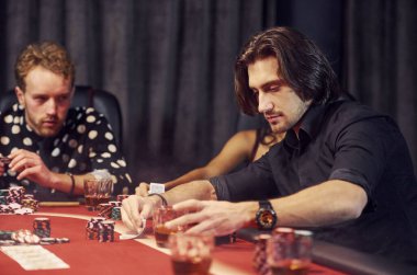 Bir bardak içkiyle. Kumarhanede birlikte poker oynayan bir grup zarif genç..