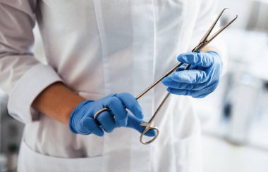 Forseps tutan kadın doktor ellerine yakından bakın..