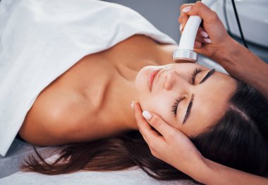 Kaplıcada uzanan ve yüz temizleme ameliyatı olan bir kadın..