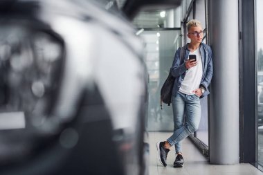 Güzel elbiseli genç hippi, gri arka plan ve arabanın yanında duruyor..