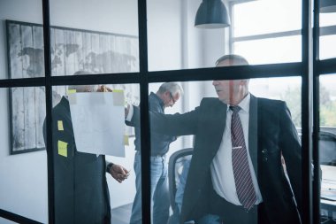 Camdaki çıkartmalarla çalışmak. Yaşlı iş adamlarından oluşan yaşlı bir ekip ofiste bir toplantı yapıyor..