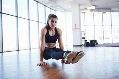 Spor kıyafetli genç bir kadın spor salonunda spor yapıyor..