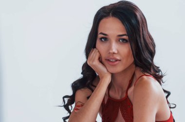 Beyaz odada kırmızı iç çamaşırlı güzel bir esmerin portresi..