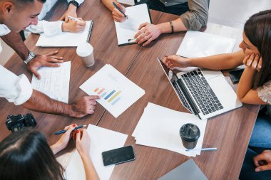 Modern ofiste doküman ve dizüstü bilgisayarla birlikte çalışan genç iş adamlarının en iyi görüşü..