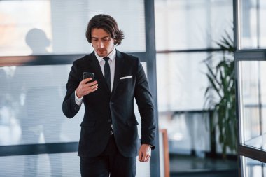 - Telefonu kullanarak. Siyah takım elbiseli ve kravatlı yakışıklı iş adamının portresi..