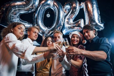 Kapı çalan gözlükler. Yeni yıl kutlamaları için ellerinde balonlar ve içkilerle neşeli bir grup insan..