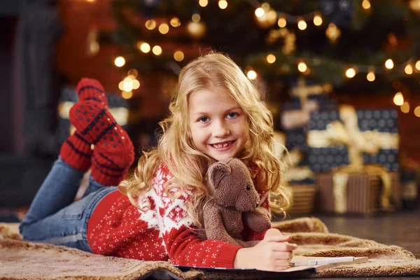 Милая Маленькая Девочка Красном Праздничном Свитере Лежит Плюшевым Мишкой Помещении — стоковое фото