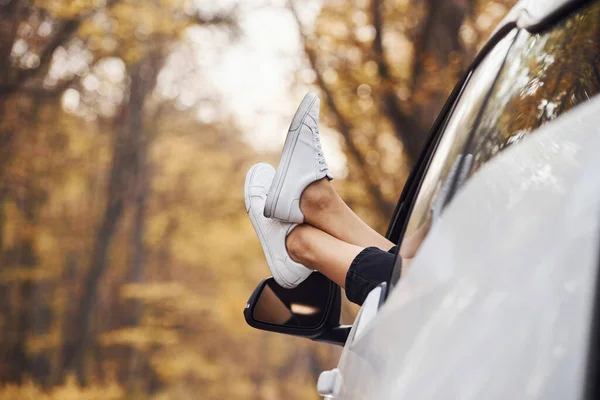 女性の足の車の窓からです 森の中の近代的なブランドの新車 — ストック写真