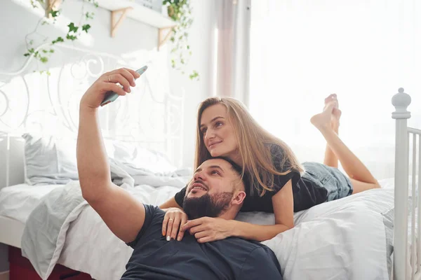 Молодая Супружеская Пара Делает Селфи Используя Телефон Спальне Днем — стоковое фото