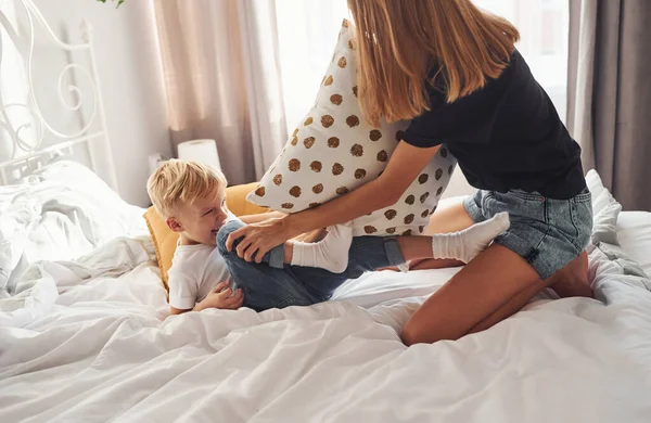 母遊び枕戦いで彼女の息子でベッドルームで昼間 — ストック写真