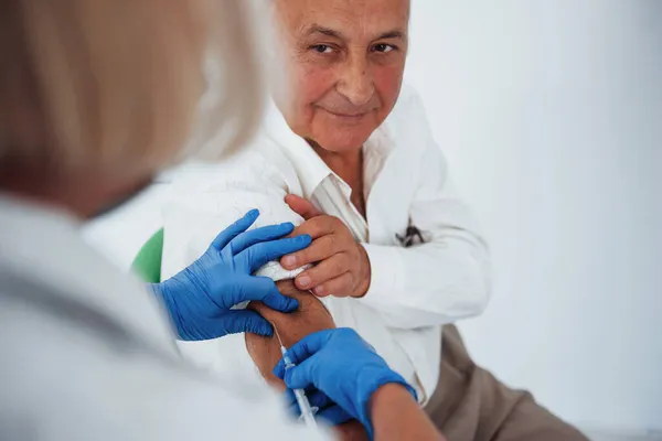 女医生在诊所向老年男性病人注射注射器 — 图库照片