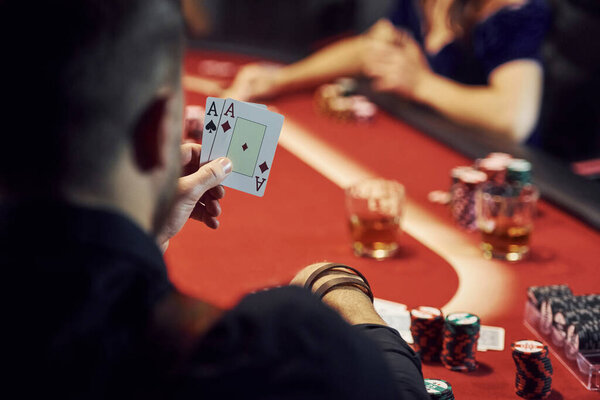 Guy have pair of aces. Group of elegant young people that playing poker in casino together.