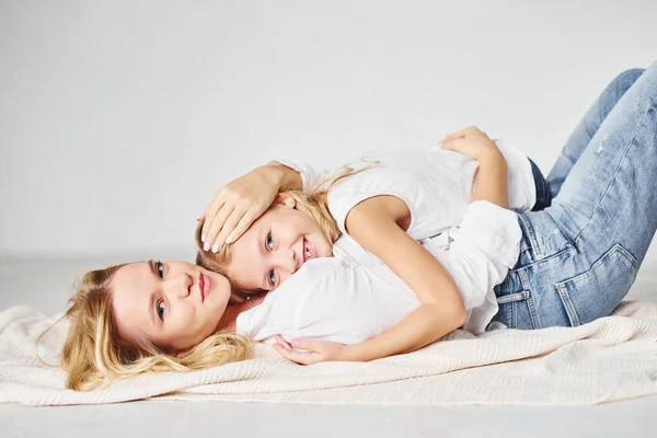 彼女の娘と一緒に母親は白い背景を持つスタジオで地面にあります — ストック写真
