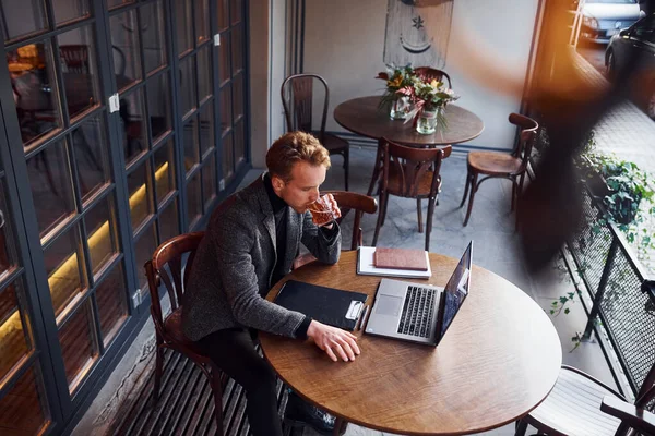 トップビューのエレガントな若いです男でフォーマルな着用でカフェに座っています彼のラップトップ — ストック写真