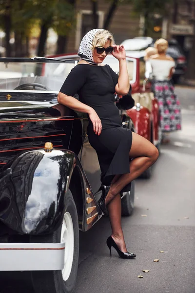 Mulher Loira Óculos Sol Vestido Preto Encostado Velho Carro Clássico — Fotografia de Stock