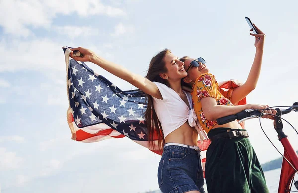 Dvě Vlastenecké Veselé Ženy Motorkou Vlajkou Usa Rukou Dělá Selfie — Stock fotografie