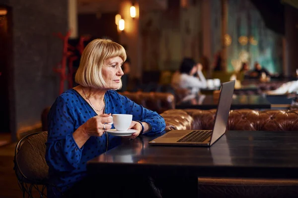 現代のラップトップでカフェ内に座っているシニア女性の肖像画 — ストック写真