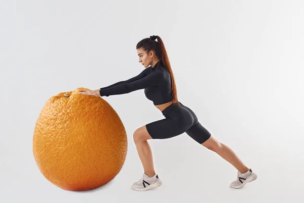 Tryckte Jätteapelsin Sportiv Kvinna Svart Kläder Studion Mot Vit Bakgrund — Stockfoto