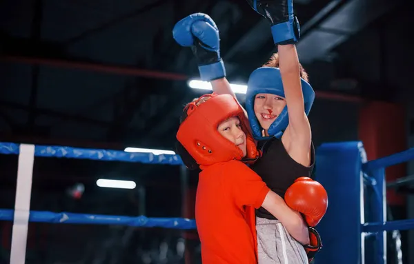 ボクシングリングで勝利を祝う保護手袋の2人の若い男の子の肖像 — ストック写真