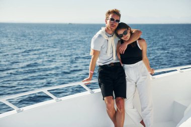 Denizdeki yatta duran neşeli genç bir çift. Tatil kavramı.