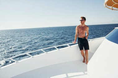 Güneş gözlüklü. Genç erkek turist denizdeki yatta. Tatil kavramı.