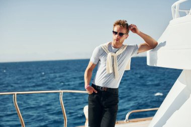 Kamera için poz vermek. Genç erkek turist denizdeki yatta. Tatil kavramı.