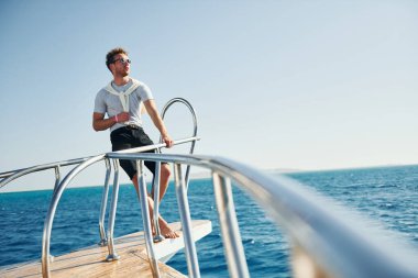 Kamera için poz vermek. Genç erkek turist denizdeki yatta. Tatil kavramı.