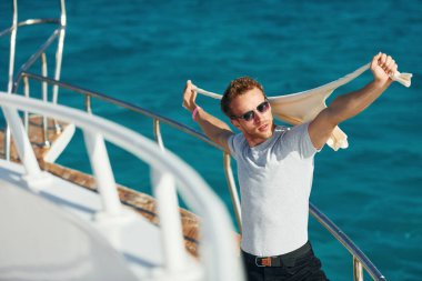Posing for a camera. Young male tourist is on the yacht on the sea. Conception of vacation.