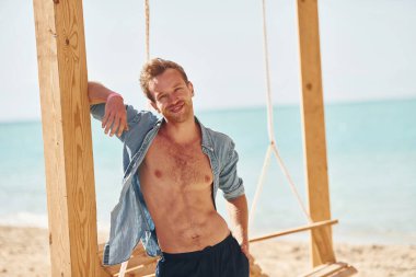 Vücudu gösteriyor. Genç Avrupalı adam tatilde ve deniz kıyısında boş zamanlarının tadını çıkarıyor..