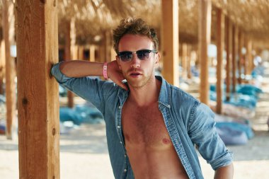 Kamera için poz vermek. Genç Avrupalı adam tatilde ve deniz kıyısında boş zamanlarının tadını çıkarıyor..