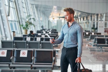 Resmi kıyafetli genç adam modern havaalanında. Tatil kavramı.