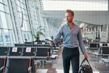 Resmi kıyafetli genç adam modern havaalanında. Tatil kavramı.
