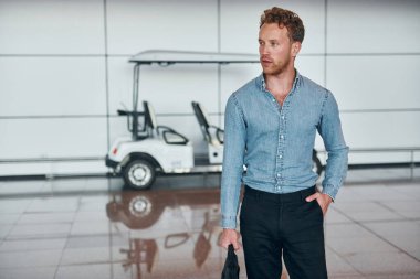 Araca karşı. Resmi kıyafetli genç adam modern havaalanında. Tatil kavramı.