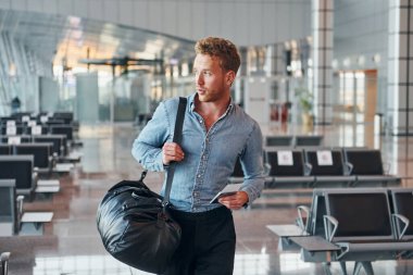 Resmi kıyafetli genç adam modern havaalanında. Tatil kavramı.
