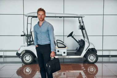 Araca karşı. Resmi kıyafetli genç adam modern havaalanında. Tatil kavramı.