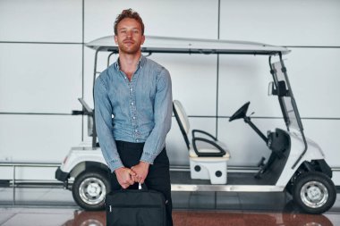 Araca karşı. Resmi kıyafetli genç adam modern havaalanında. Tatil kavramı.