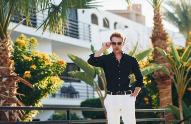 Güneş gözlüklü. Genç adam güneşli bir günde dışarıda. Tatil kavramı.