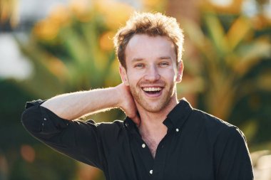 Genç adam güneşli bir günde dışarıda. Tatil kavramı.