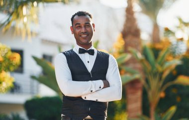 Kamera için poz vermek. Resmi kıyafetli zenci garson güneşli bir günde iş yerinde..