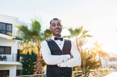 Kamera için poz vermek. Resmi kıyafetli zenci garson güneşli bir günde iş yerinde..